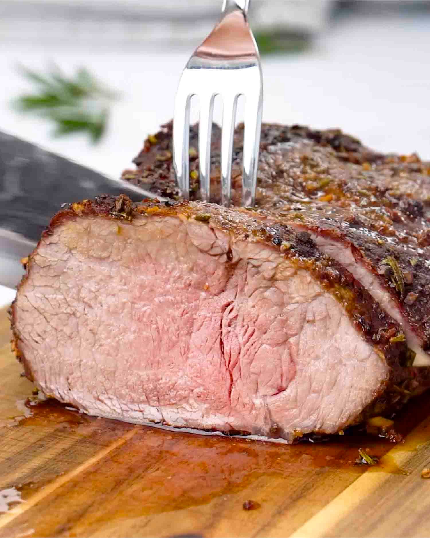 a roast beef made in the air fryer sliced on a cutting board.