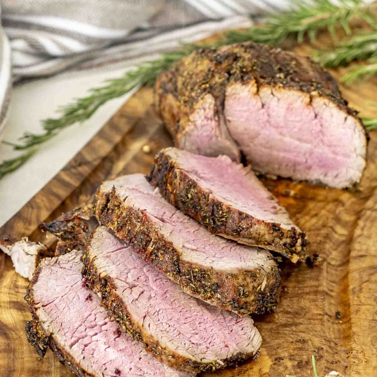 a roast beef made in the air fryer sliced on a cutting board.