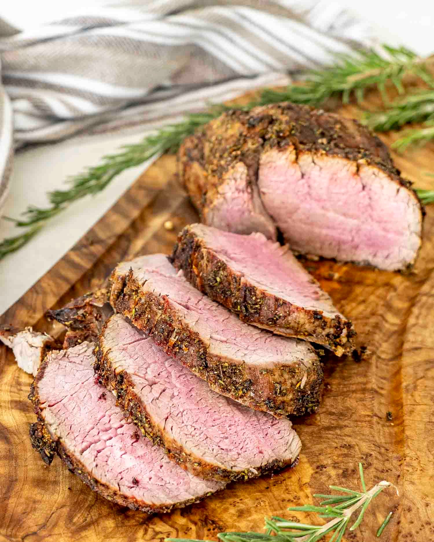 a roast beef made in the air fryer sliced on a cutting board.