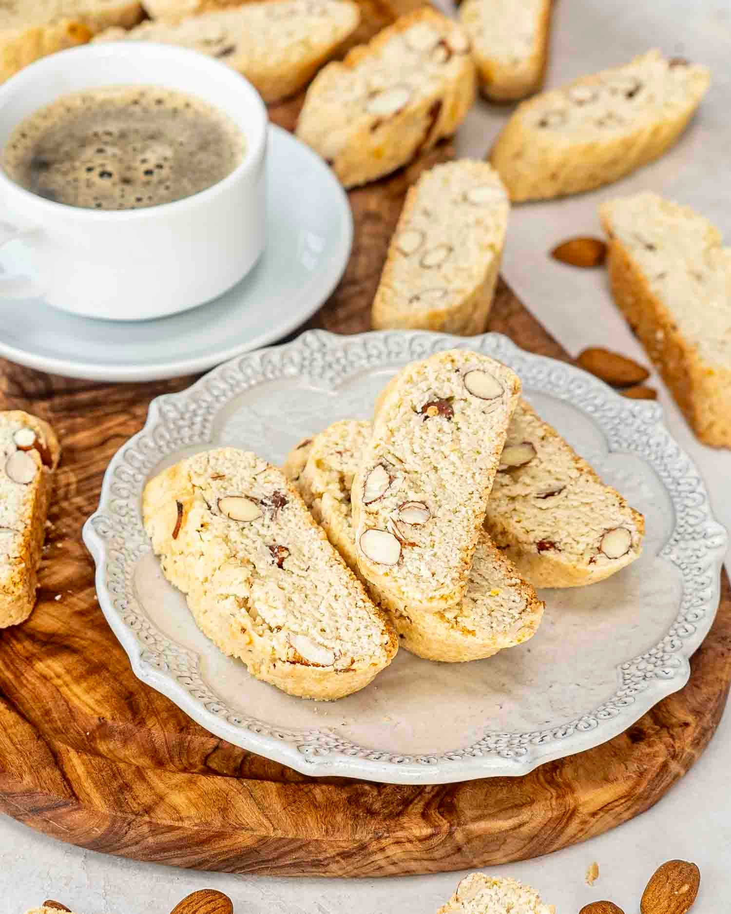 almond biscotti with a cup of coffee on a cutting board.