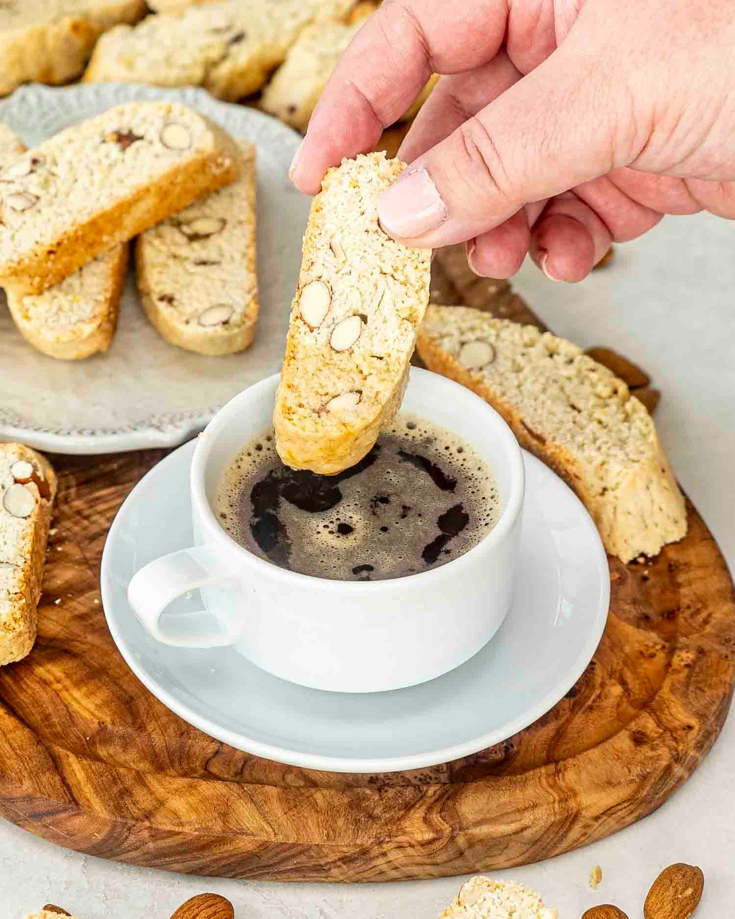 almond biscotti with a cup of coffee on a cutting board.