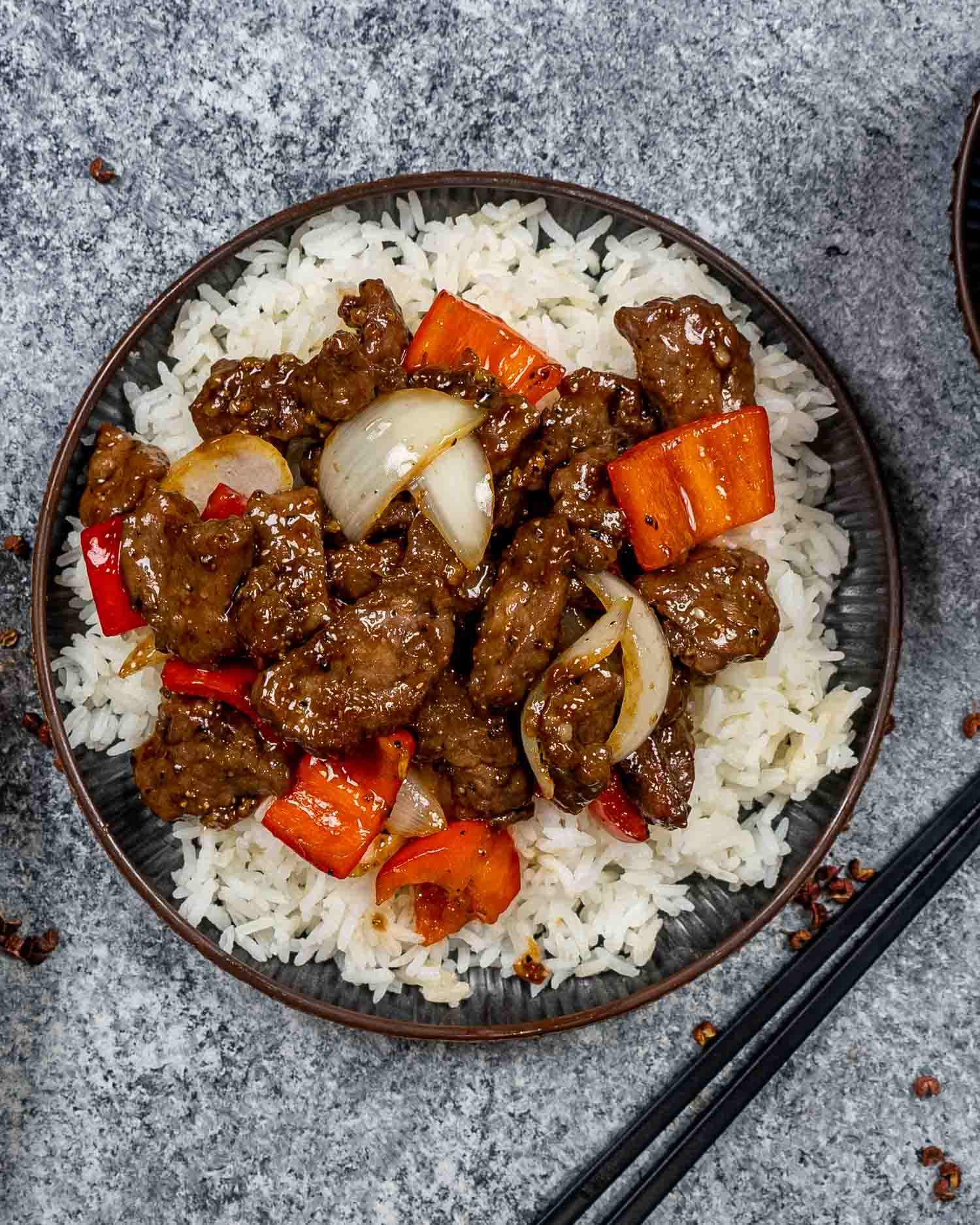 a serving of black pepper beef over a bed of rice.