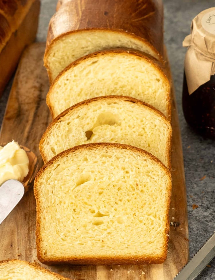 a brioche bread cut in slices on a cutting board.