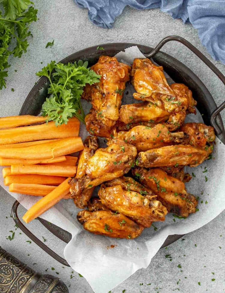 baked buffalo chicken wings with a blue cheese dip in a little dish.