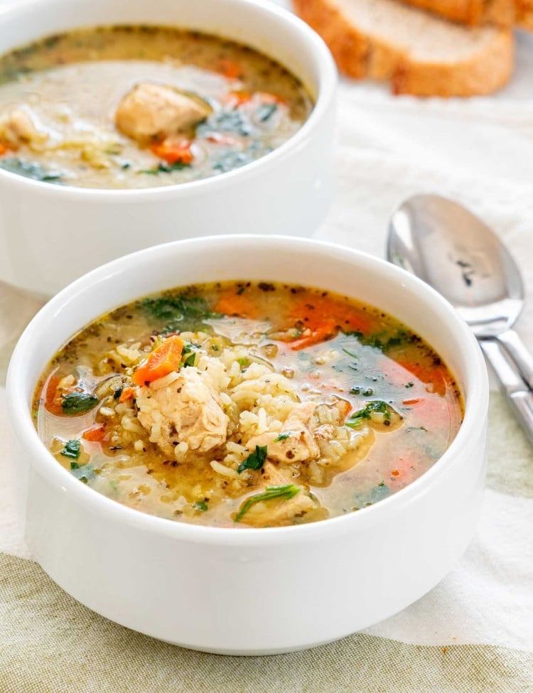side view shot of two bowls of chicken and rice soup.