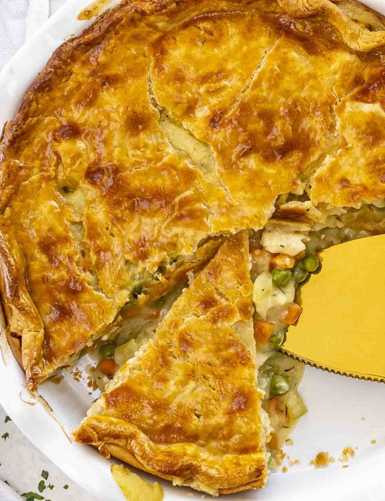 chicken pot pie in a white pie dish with slice removed.