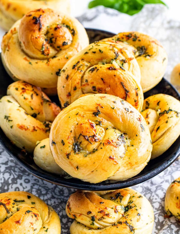 side view shot of garlic knots in a bread bowl with some garlic knots surrounding the bowl