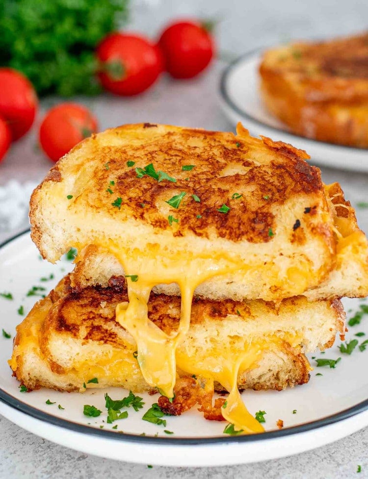 a grilled cheese sandwich cut in half and stacked on a white plate.