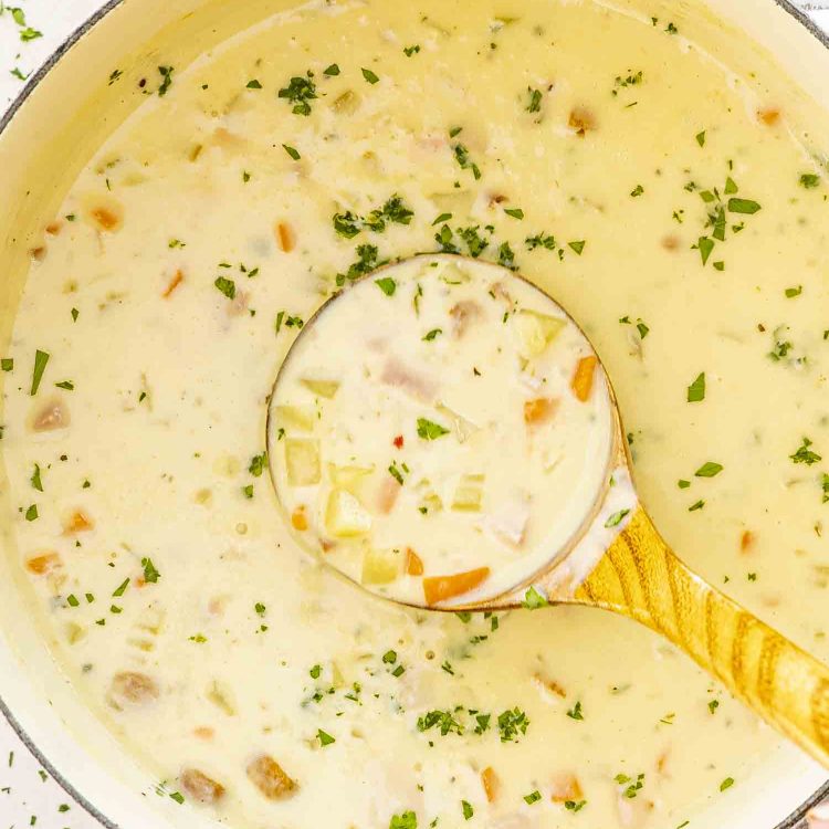 freshly made ham and potato soup in a beige dutch oven.