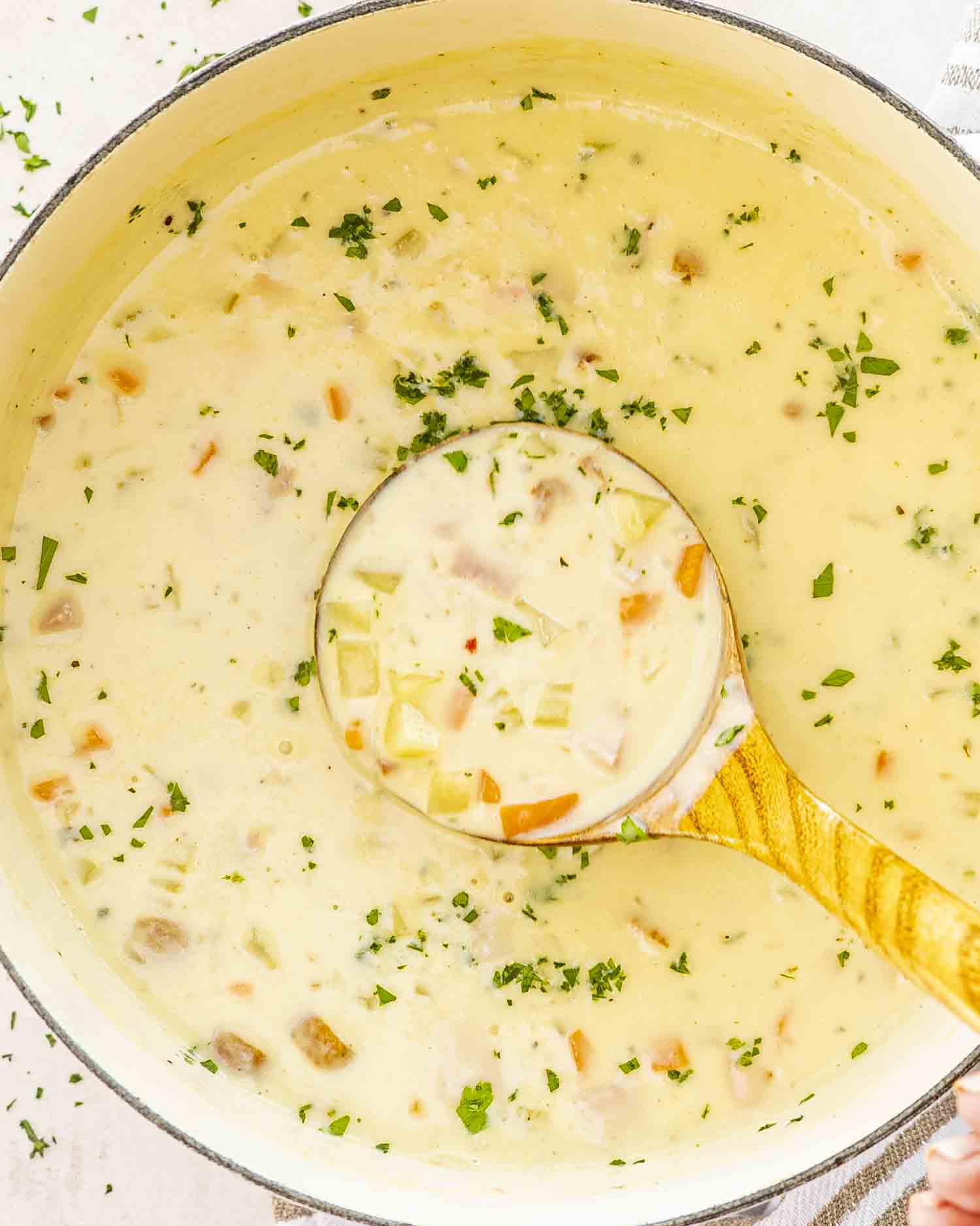 freshly made ham and potato soup in a beige dutch oven.