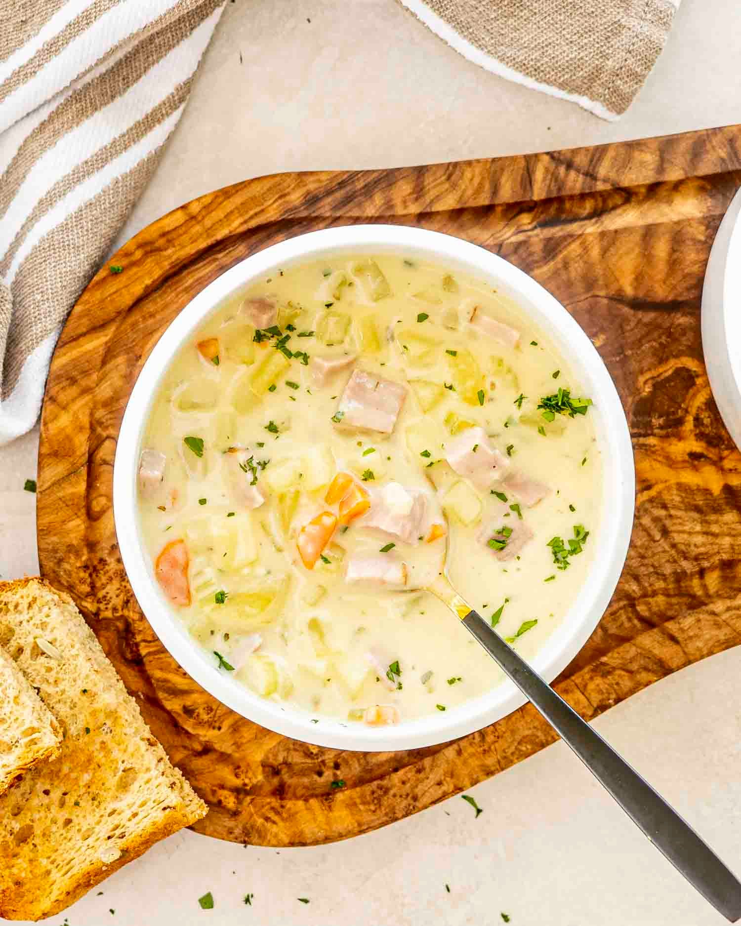 a white bowl of ham and potato soup.
