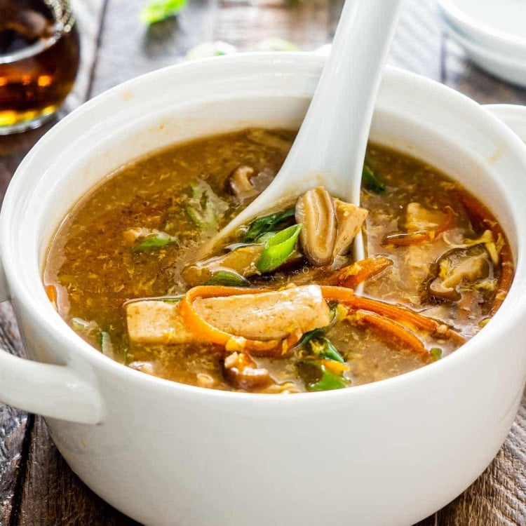 hot and sour soup in a white bowl with a white spoon inside.