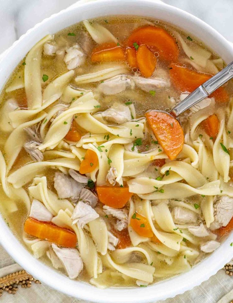 a serving of leftover turkey noodle soup in a white bowl.