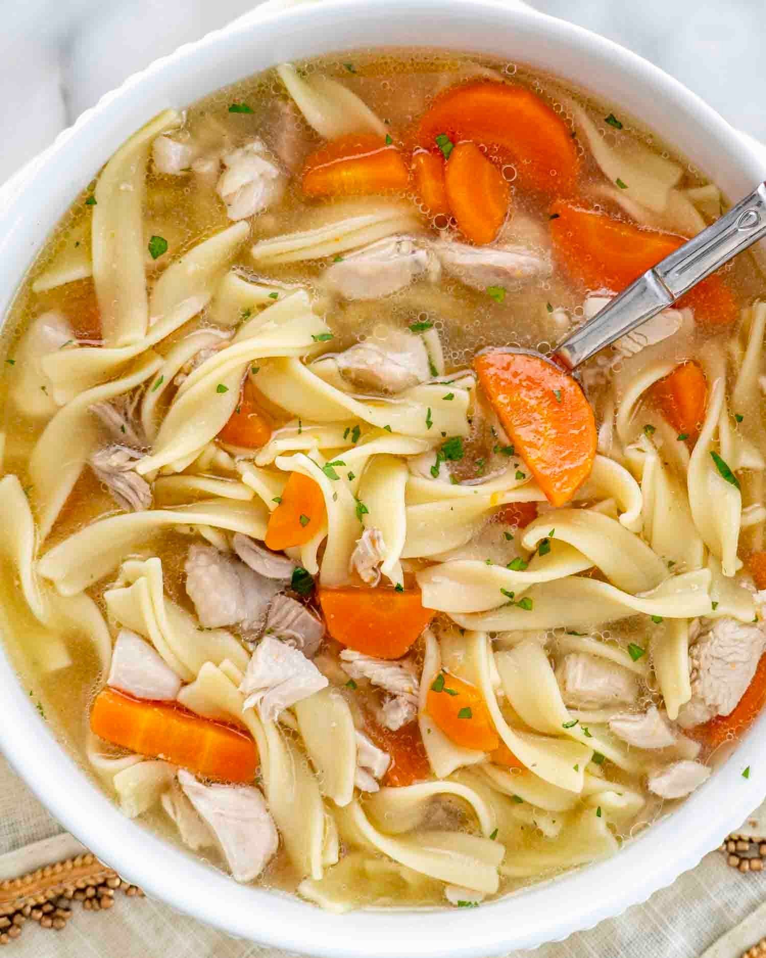 a serving of leftover turkey noodle soup in a white bowl.