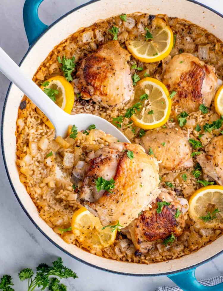 lemon chicken rice bake in a blue dutch oven garnished with parsley.