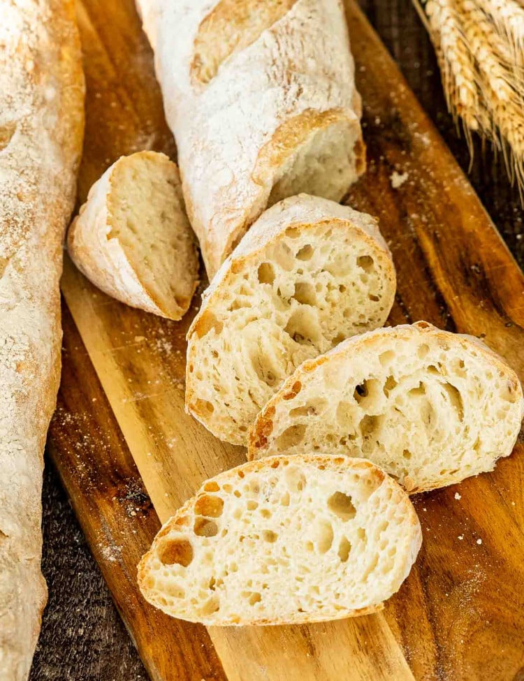 a sliced no knead baguette on a cutting board.
