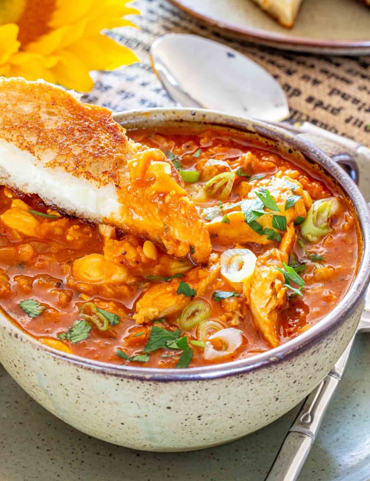 red lentil chicken soup garnished with parsley and green onions in a bowl along side some grilled cheese.
