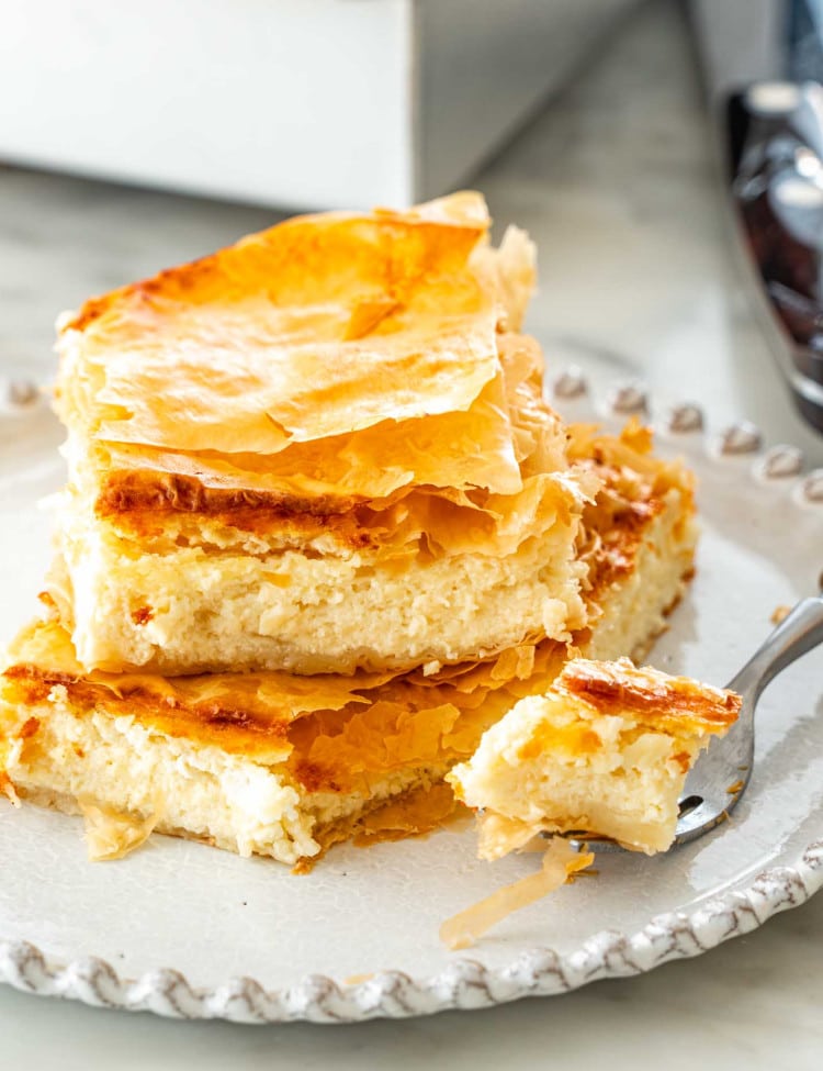 two slices of tiropita stacked on top of each other on a white plate.